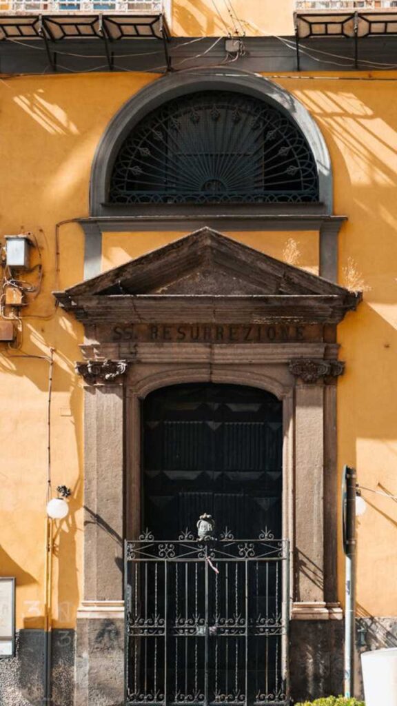 Historic building entrance with arched window and gate in Naples, Italy