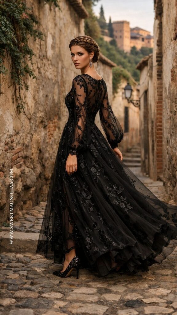 Bride in an embroidered black lace wedding gown with long sheer sleeves and a voluminous skirt, walking through a cobblestone street in an elegant modern bridal look.