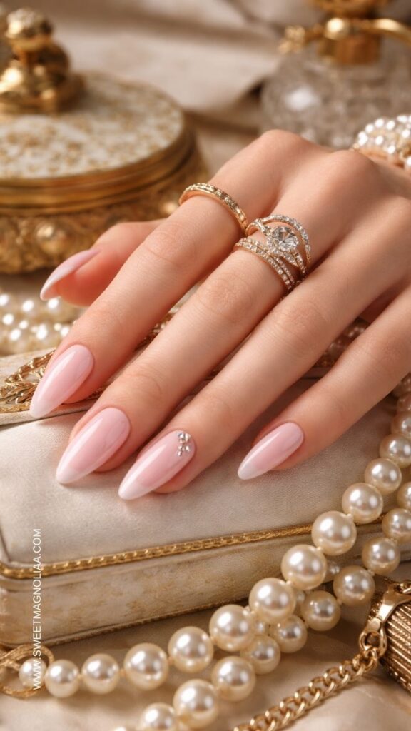 Soft blush pink almond nails with a glossy finish and a small rhinestone cluster accent creating a minimalist elegant manicure with subtle sparkle.