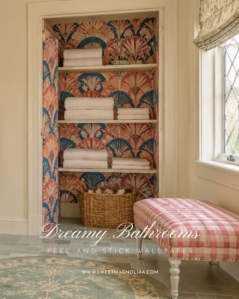 Linen closet lined with coral and navy fan pattern peel and stick wallpaper, folded white towels and a woven basket beside a pink gingham bench
